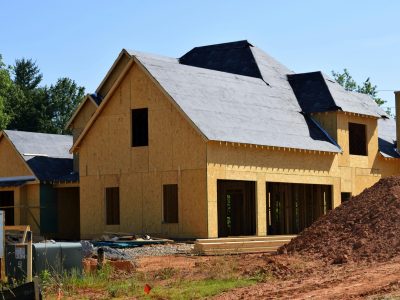 A partially built wooden house under construction, showcasing its progress and design in daylight.